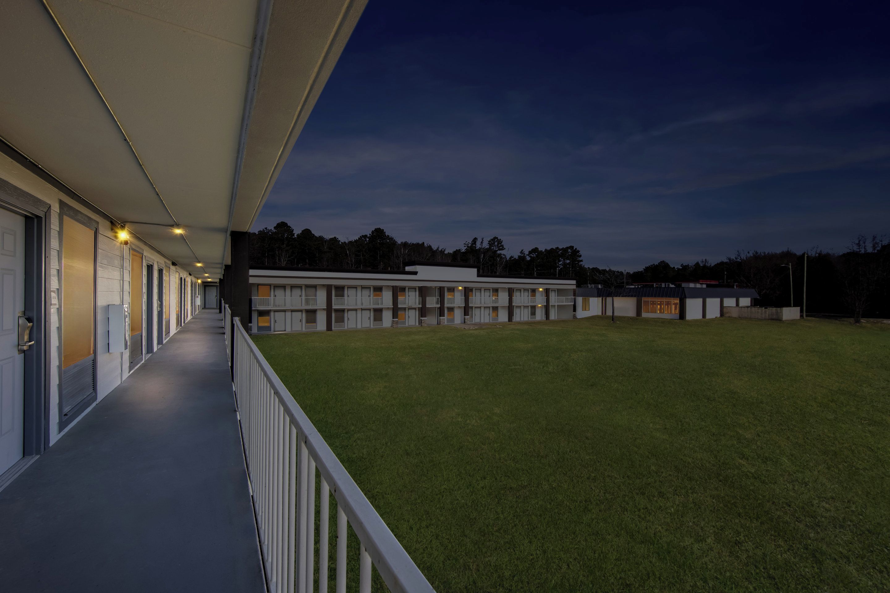 A building with a covered walkway and a grassy lawn.