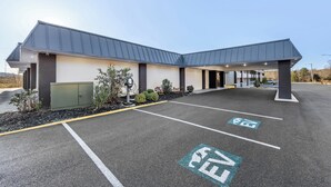 A modern building with a flat roof and a covered entrance. There are designated parking spaces for bicycles and cars. - HomeTowne Studios by Red Roof Athens, TN (Athens)
