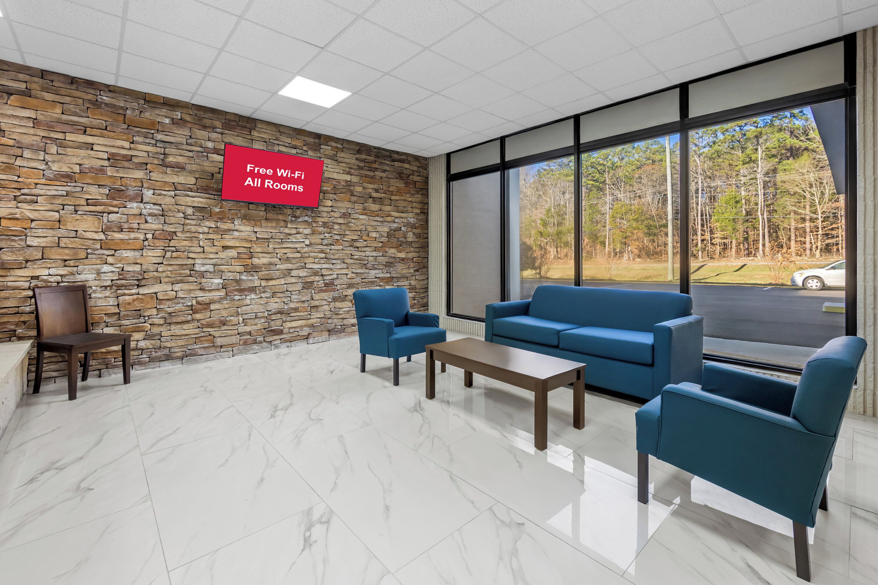 A modern waiting area with stone walls, a large window offering a view of trees and a road, and a sign indicating free Wi-Fi availability.