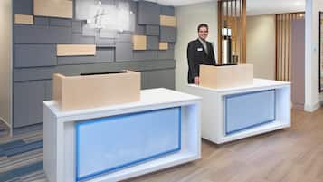 A reception area with two reception desks, a wall-mounted sign, and a wooden partition.