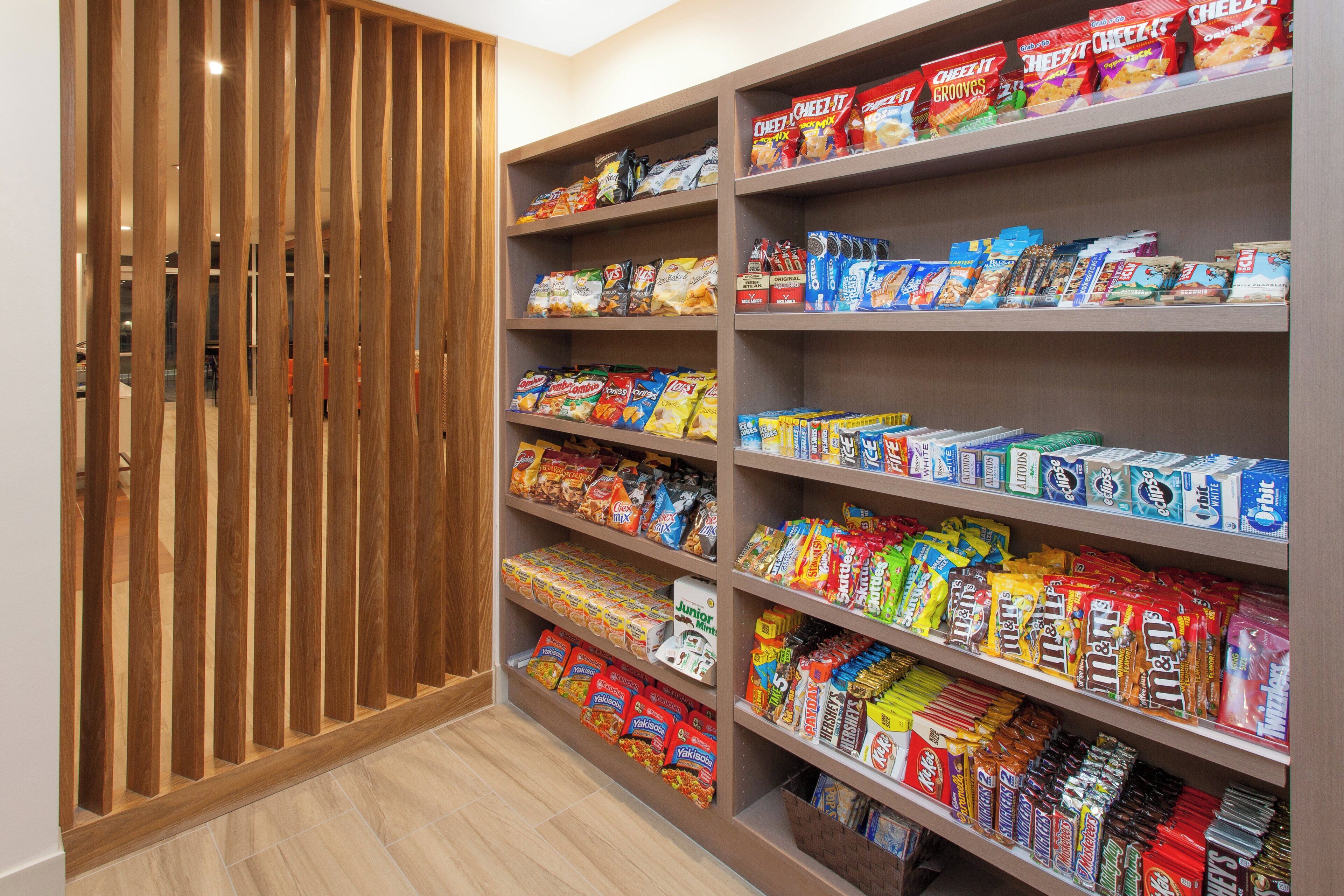 A snack aisle with various packaged snacks and a wooden slatted door.