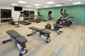 Ein Fitnessstudio mit Laufbändern, Crosstrainern und Bänken.