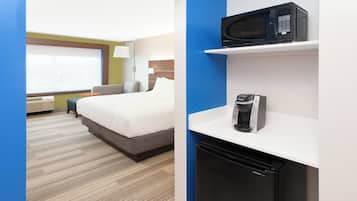 Quarto de hotel com cama, micro-ondas, cafeteira e pequeno frigorífico.