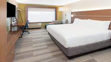 Habitación de hotel con una cama grande, un escritorio, una silla, un televisor y una ventana.