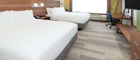 A hotel room with two beds, a desk, a chair, a TV, and a window with blinds.
