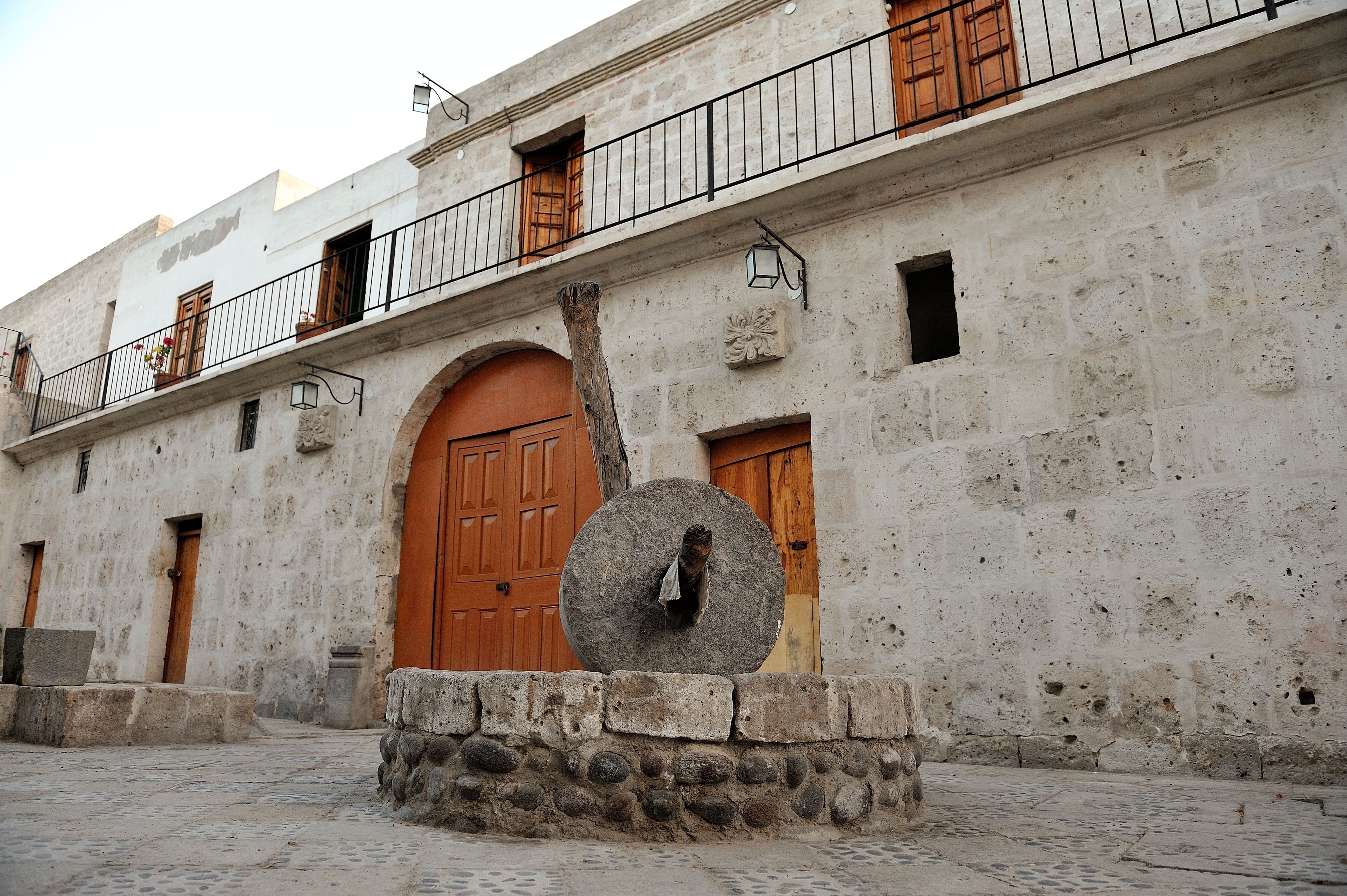 A historic building with a stone facade, a large wooden door, and a balcony with metal railings.
