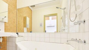 A modern bathroom with a large bathtub, a shower, and a mirror. - Cranbourne Motor Inn (Cranbourne)