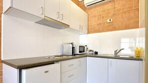 A compact kitchen with white cabinets, a microwave, and a sink. - Cranbourne Motor Inn (Cranbourne)