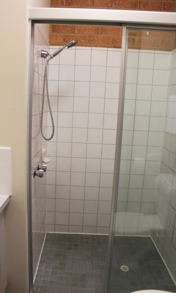 A small, enclosed shower area with a glass door, tiled walls, and a visible drain.