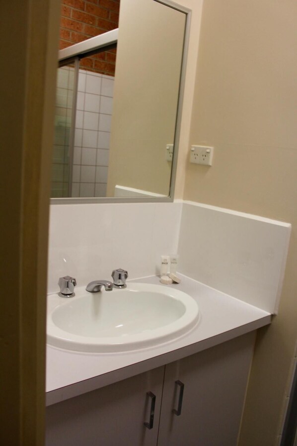 Un baño con un lavamanos blanco, un espejo y una encimera blanca.