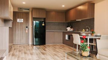 A modern kitchen with wooden cabinets, a black refrigerator, and a dining area with a glass table and chairs.
