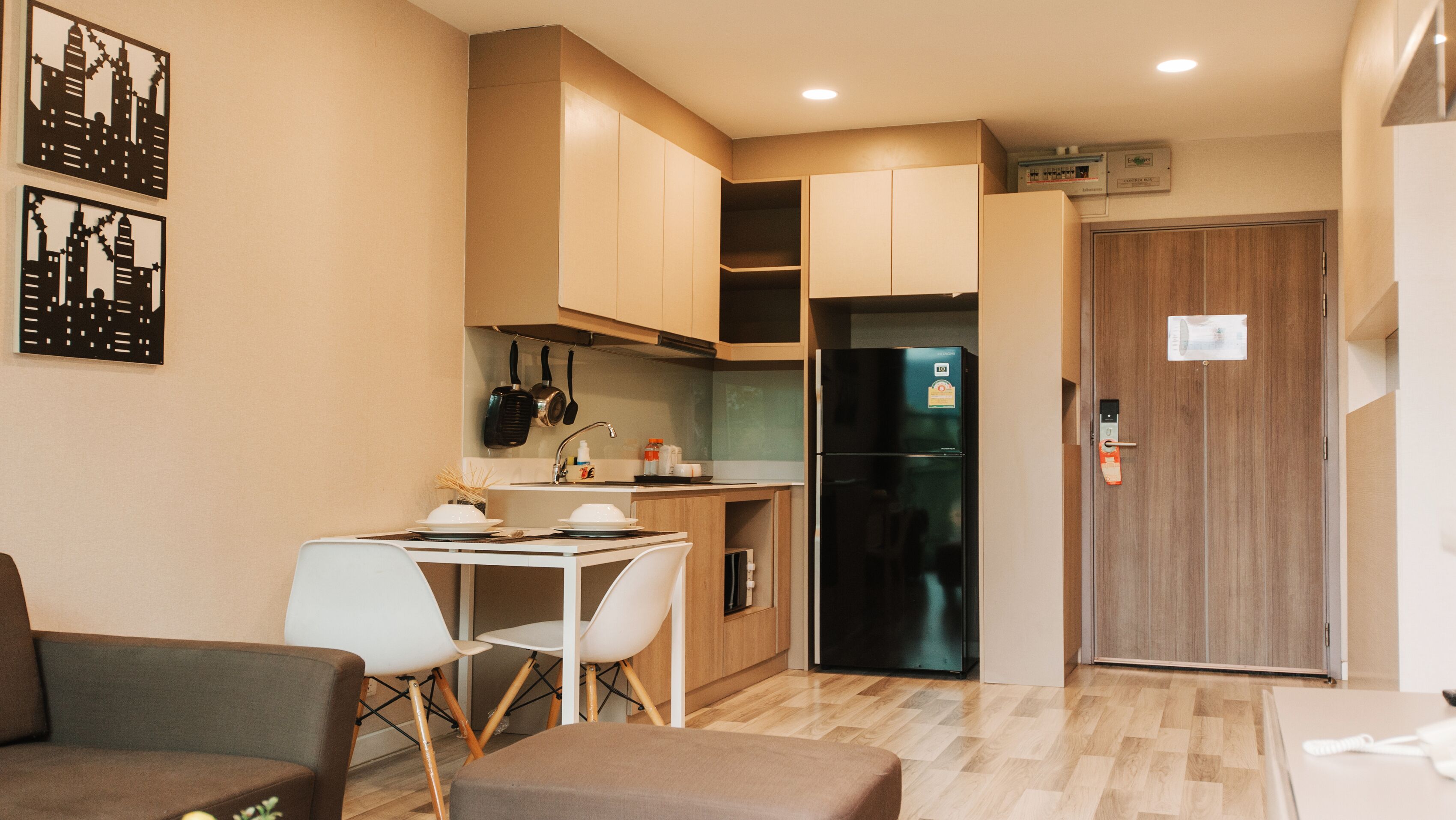 A compact kitchen with a dining area, a refrigerator, and a wooden door.