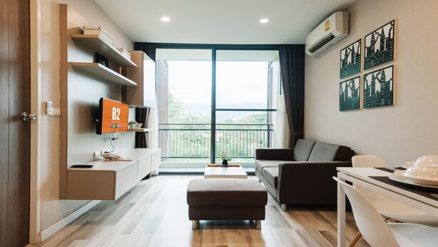 A modern hotel room with a large balcony, a flat-screen TV, a sofa, a dining table, and a wooden floor. - B2 Mountain Pano Residence Chiang Mai (Chiang Mai)