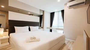 A modern hotel room with a large bed, a bedside table, a mirror, and a window with curtains. - B2 Mountain Pano Residence Chiang Mai (Chiang Mai)