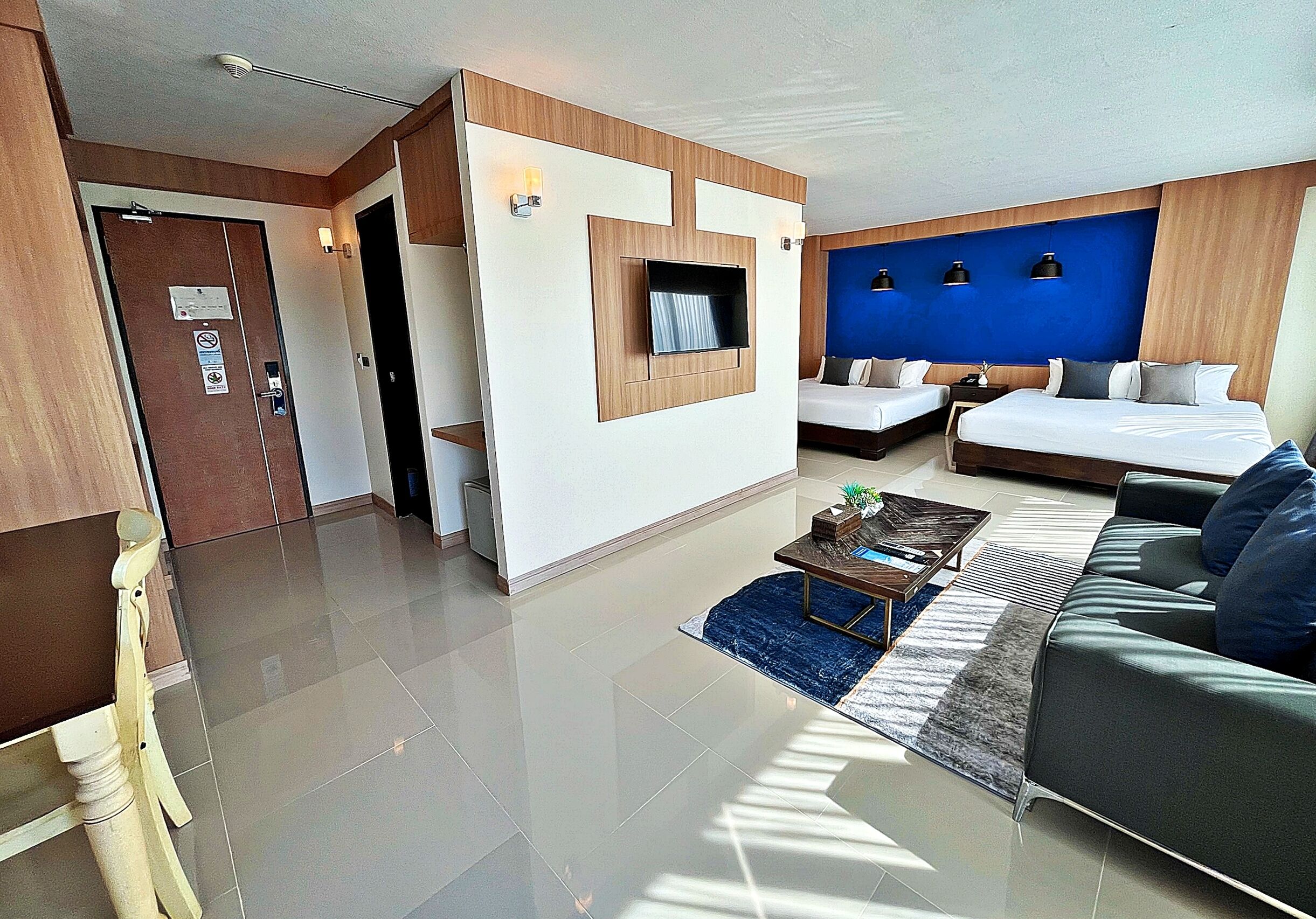 Una habitación de hotel moderna con una cama grande, un sofá, un escritorio y un televisor montado en la pared.