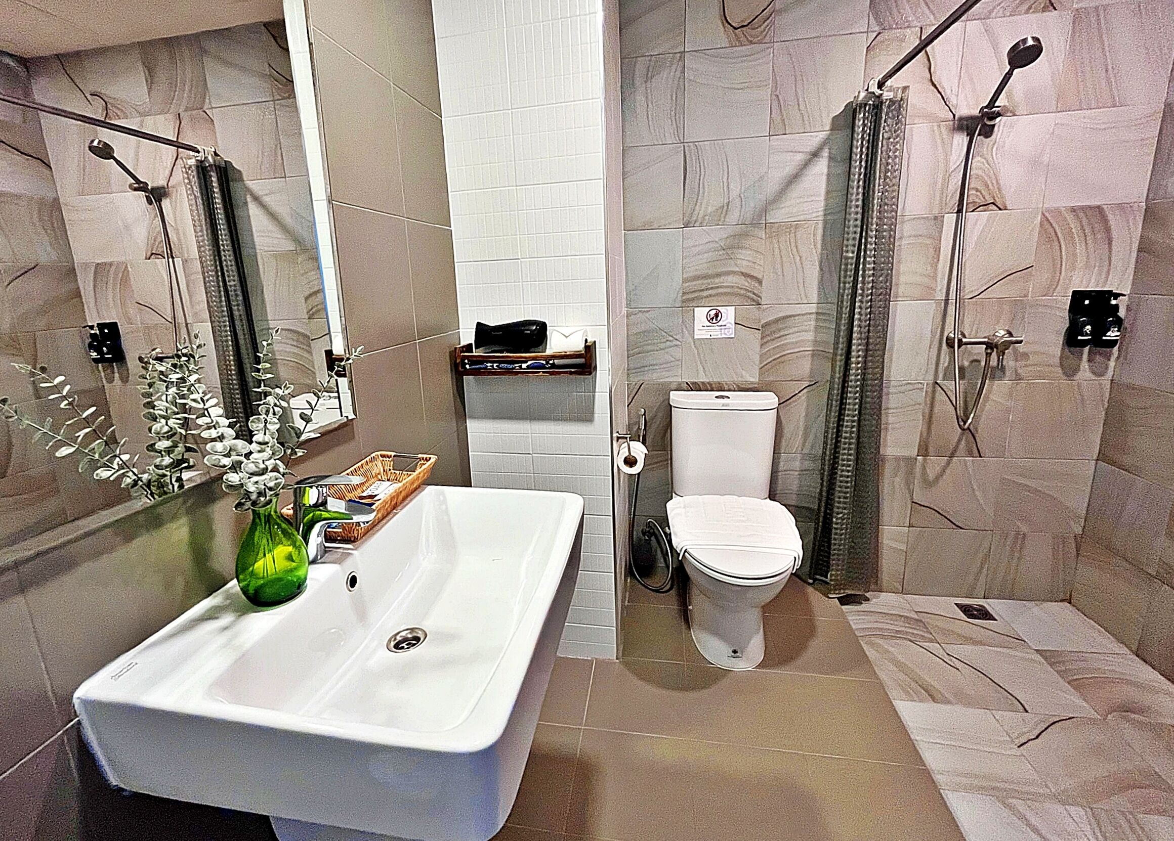A modern bathroom with a large white sink, a toilet, and a shower area.