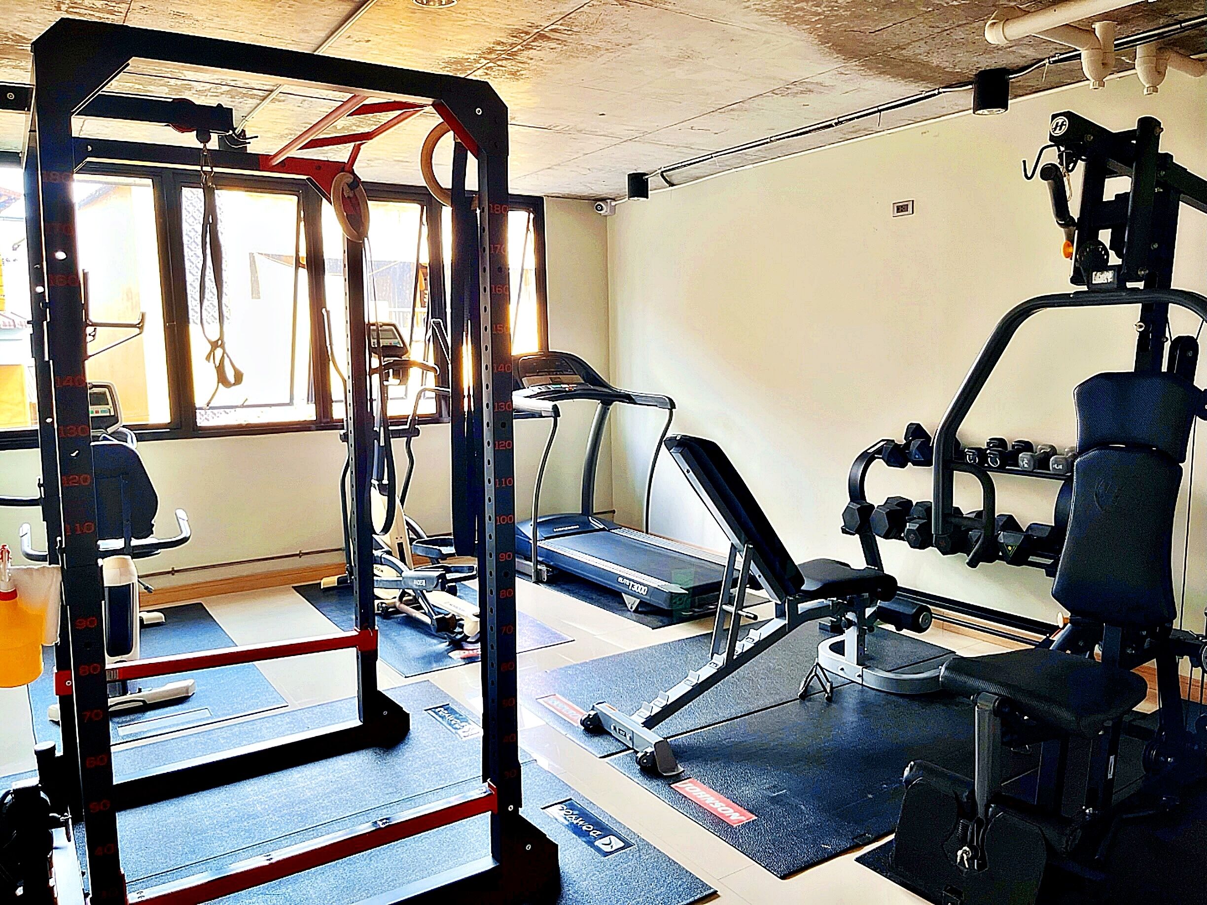 A gym with a treadmill, weight machines, and a pull-up bar.