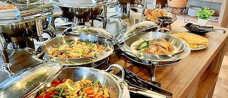 A buffet with various dishes, including stir-fried vegetables, a pot of soup, and a dish with chicken and vegetables.