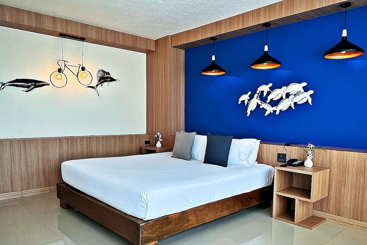 A modern bedroom with a large bed, wooden headboard, and a blue accent wall.