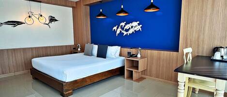A modern bedroom with a large bed, a wooden nightstand, a desk, and a blue accent wall with wall art.