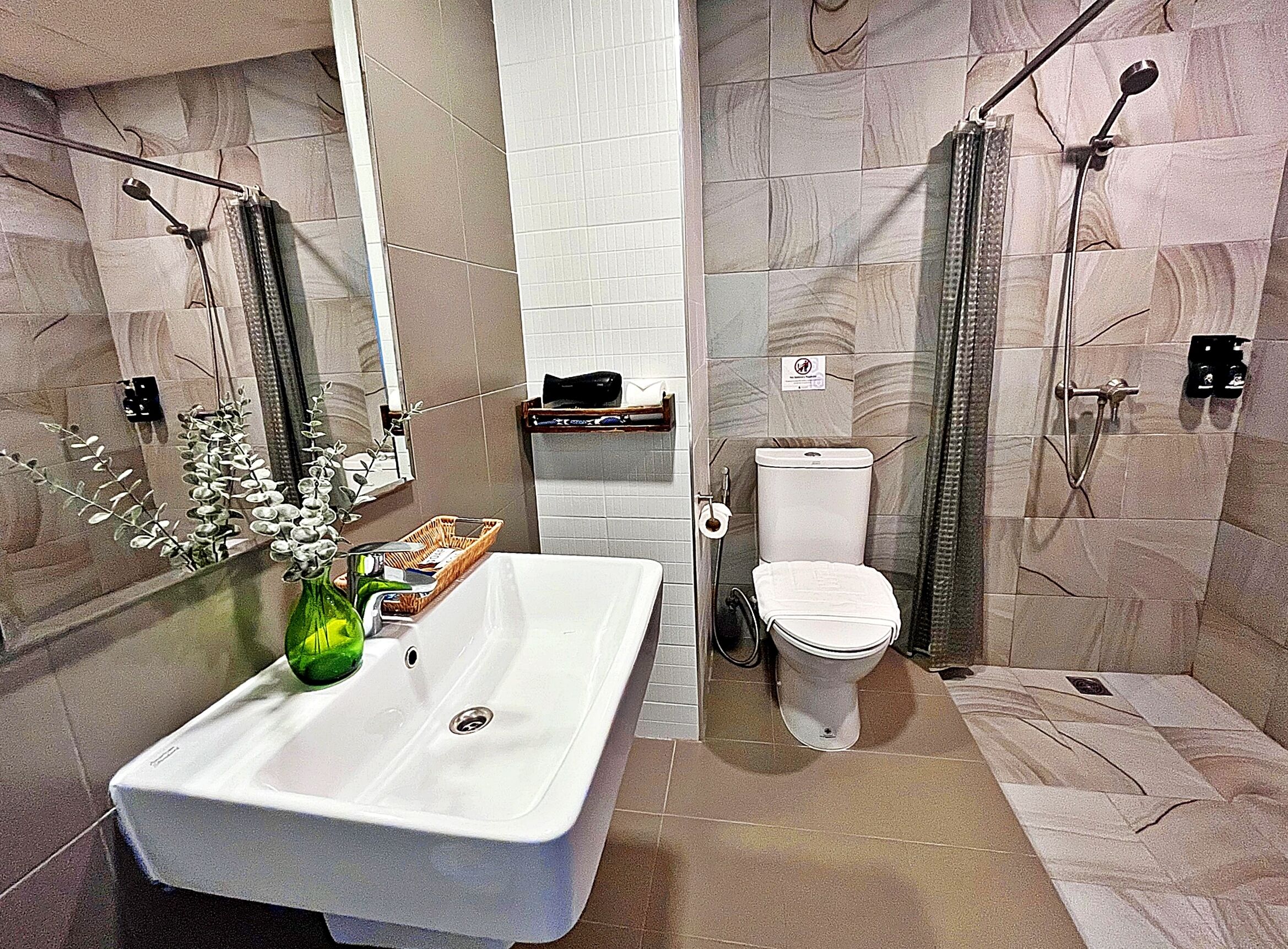 Un baño moderno con un lavamanos grande de color blanco, un inodoro y una zona de ducha.