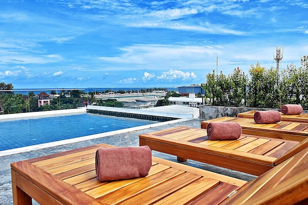 Una piscina al aire libre, sillones reclinables de piscina