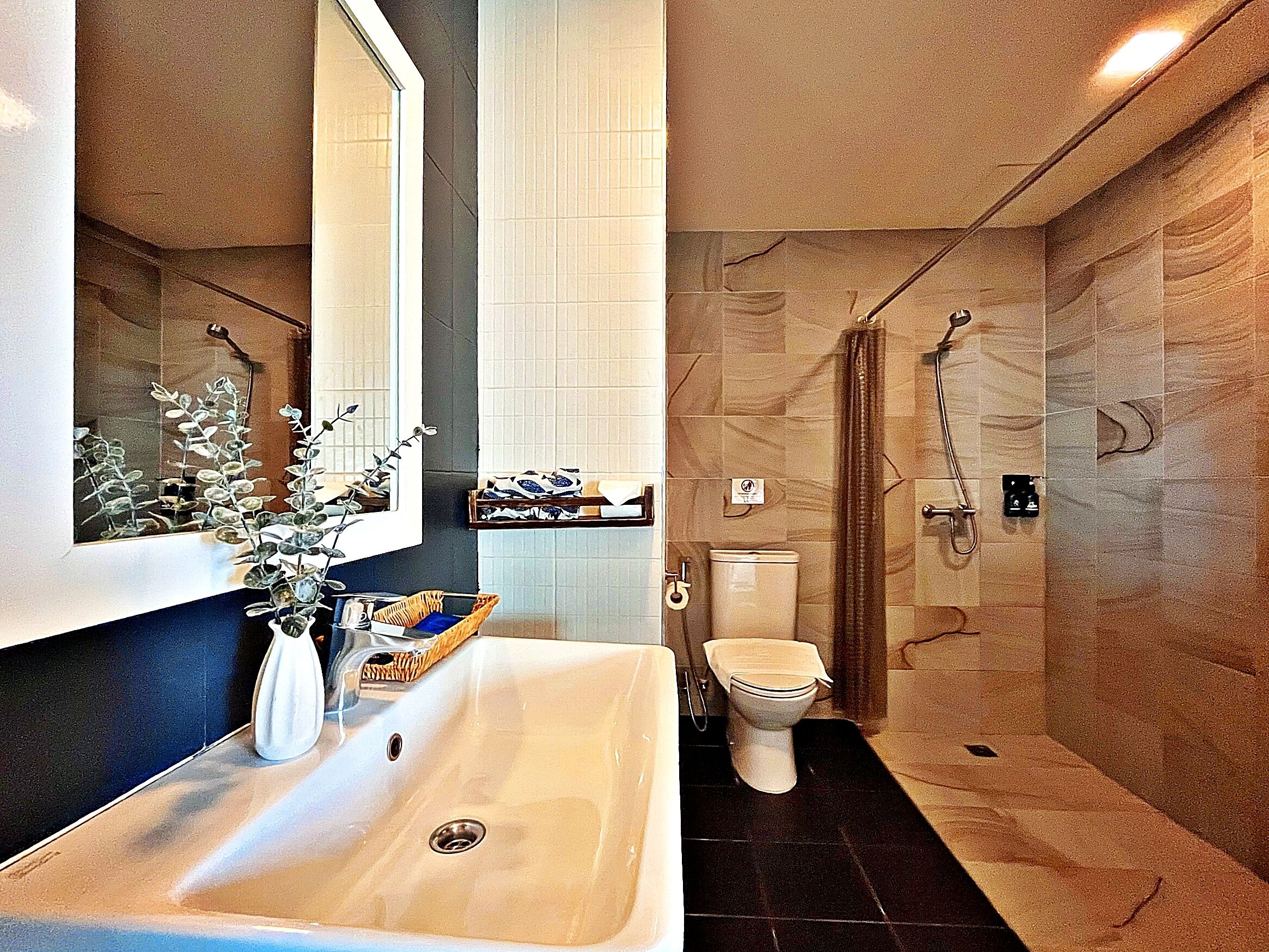 A bathroom with a sink, mirror, toilet, and shower.
