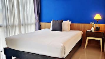 A hotel room with a large bed, a nightstand with a lamp, and a wall decoration of sea turtles.