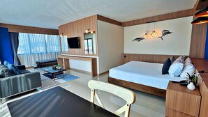 Moderni hotellihuone, jossa on suuri sänky, työpöytä, sohva ja ruokapöytä.