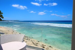 Vista de una playa con aguas turquesas cristalinas, una orilla arenosa y una silla blanca.