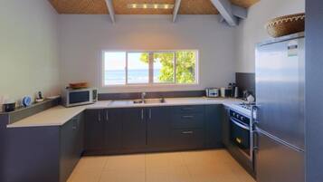 A modern kitchen with dark cabinets, a microwave, a sink, and a refrigerator.