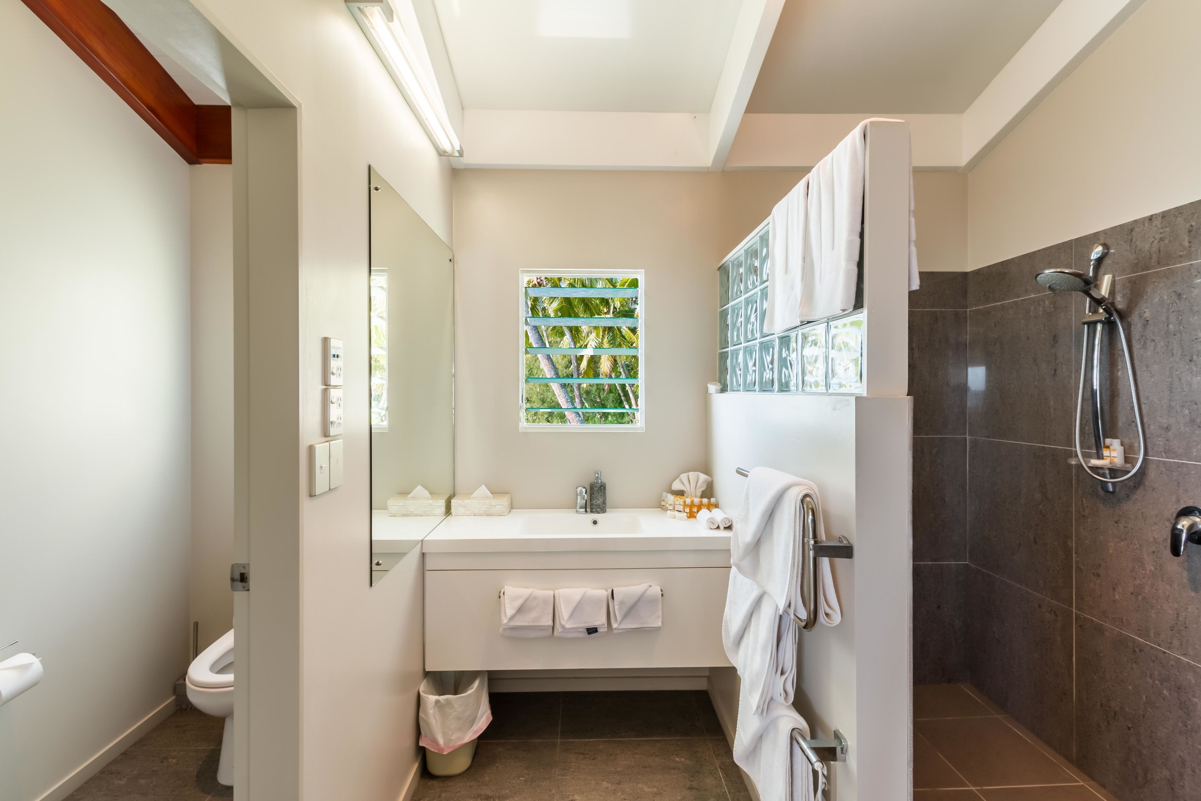 A modern bathroom with a shower, a sink, and a toilet.