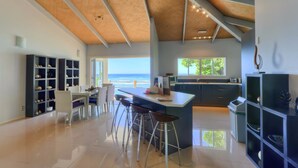 A modern kitchen with a large island, bar stools, and built-in shelving. - Ocean Spray Villas (Rarotonga)