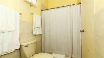 A bathroom with a toilet, a shower curtain, and two towels hanging on hooks.
