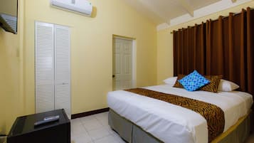 Quarto de hotel com cama, televisão, guarda-roupa e ar condicionado.
