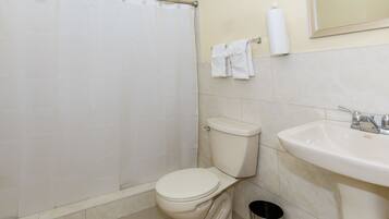 Un baño con inodoro, lavamanos y cortina de ducha.