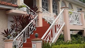 Un edificio con escalera roja, barandillas blancas y ventanas de arco.