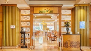 Un hall d'hôtel avec une enseigne indiquant un « café-jardin », un comptoir d'accueil et un espace détente avec des tables et des chaises.