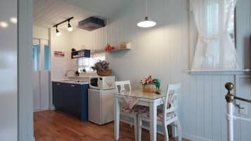 A compact kitchen with wooden cabinets, a microwave, and a dining area with a table and chairs.