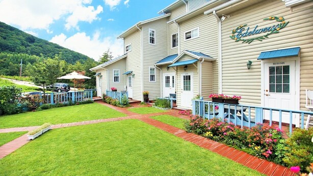A hotel with a well-maintained lawn, a blue fence, and a sign reading "Edelweiss." - Edelweiss Pension (Pyeongchang)