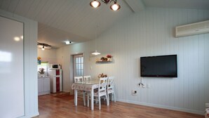 A spacious living area with a dining table, chairs, and a flat-screen TV mounted on the wall. - Edelweiss Pension (Pyeongchang)
