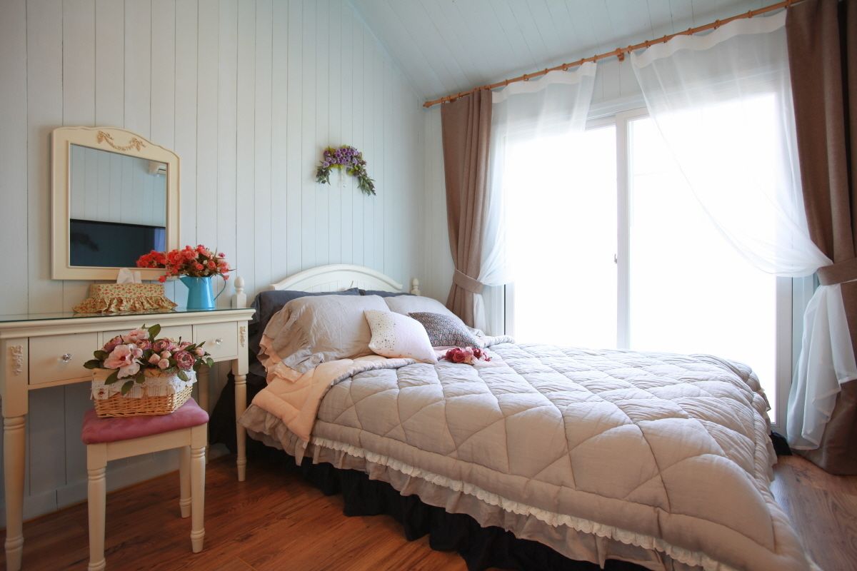 Un dormitorio con cama, cómoda, espejo y ventana con cortinas.