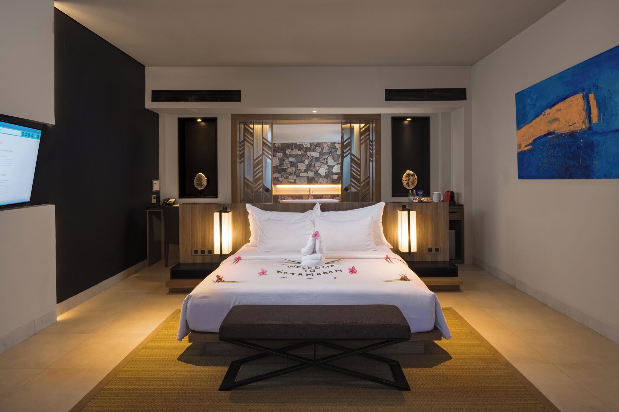 Ein modernes Hotelzimmer mit einem großen Bett, Nachttischen, einem Schreibtisch und einem an der Wand montierten Fernseher.