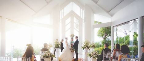 Une cérémonie de mariage avec une allée blanche et des invités assis sur des chaises blanches.