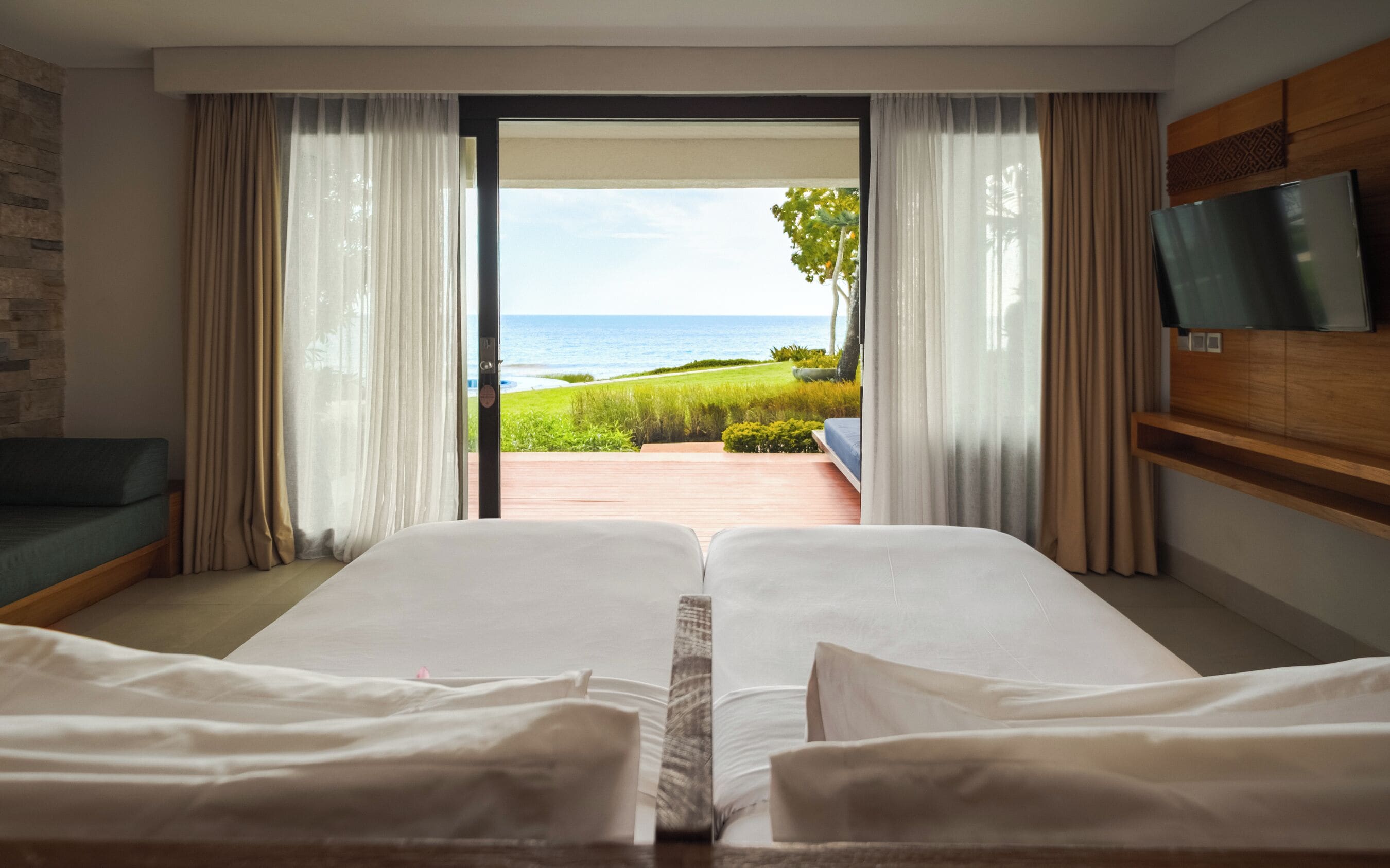 Habitación de hotel con dos camas, televisión y vista al océano.