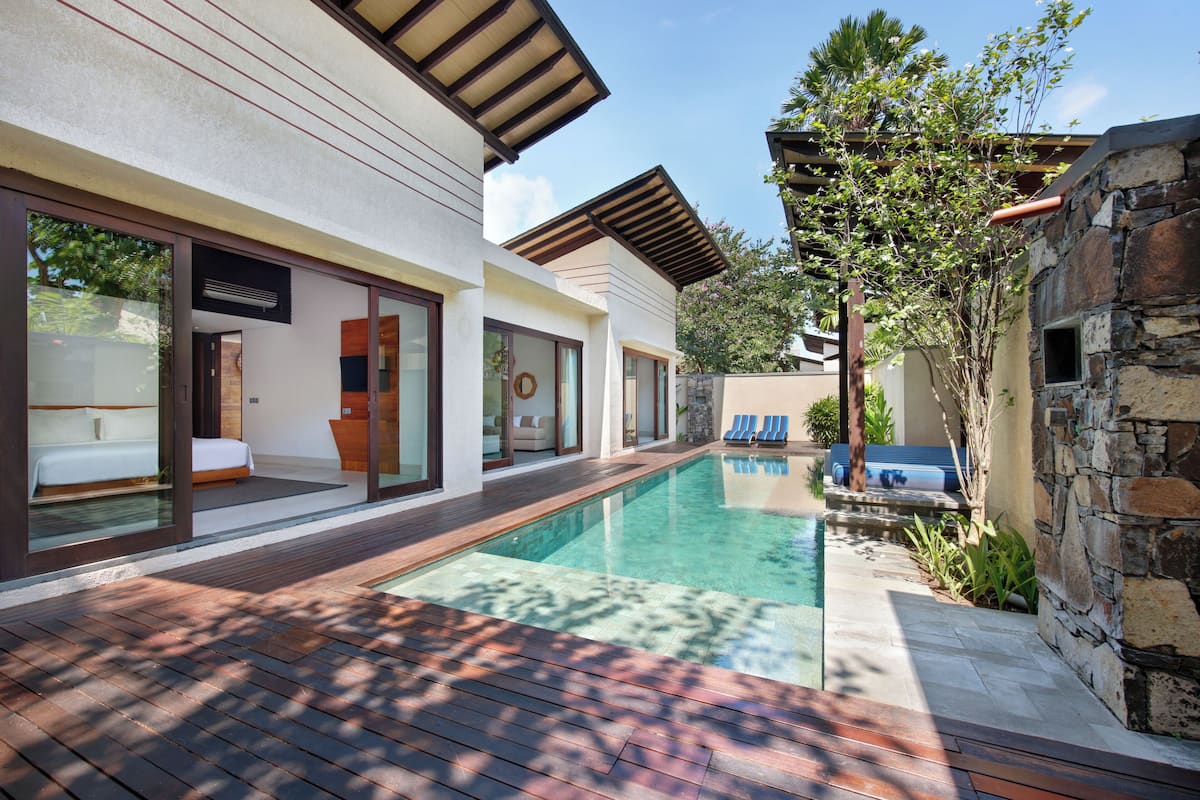 A modern house with a swimming pool, wooden deck, and stone walls.