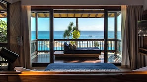 A room with a large window, a bed, a wooden desk, and a view of the ocean. - Katamaran Hotel & Resort Lombok (Senggigi)