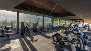 Un gimnasio moderno con diverso equipo de ejercicio, amplias ventanas y techo de madera.