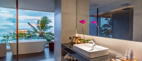 A modern bathroom with a large bathtub, a white sink, and a large mirror.