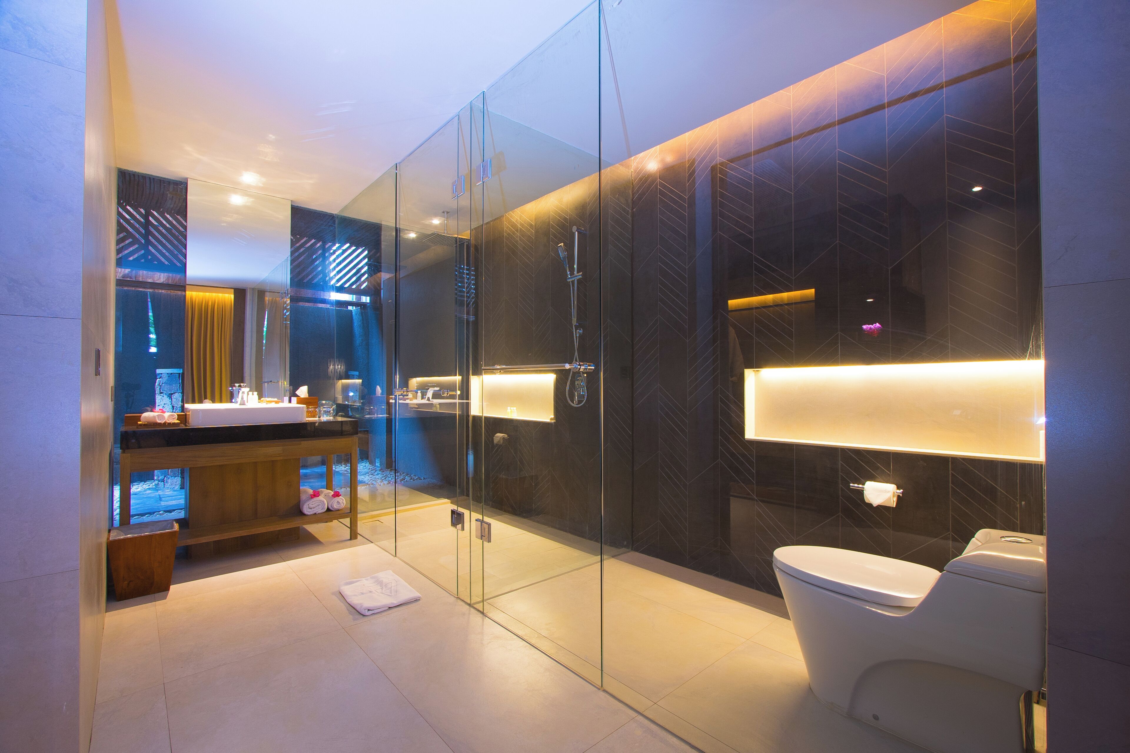 A modern bathroom with a glass-enclosed shower, a vanity with a sink, and a toilet.